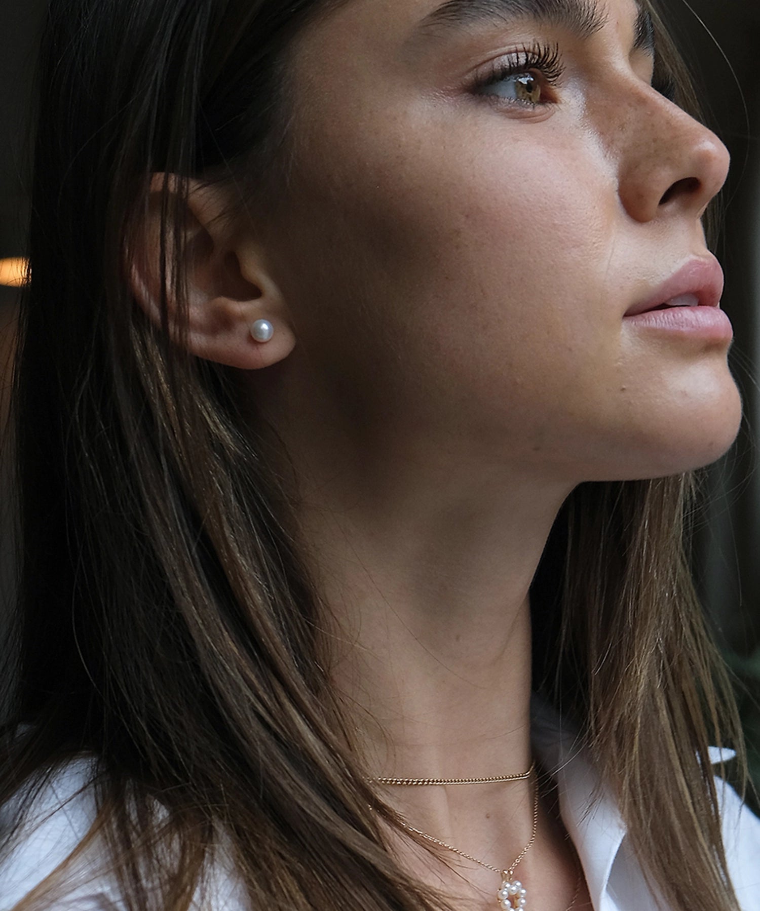 14kt Gold Mini Studs - 6-7mm white round freshwater pearl earrings in 14kt yellow gold by Nishi Pearls, worn on a model