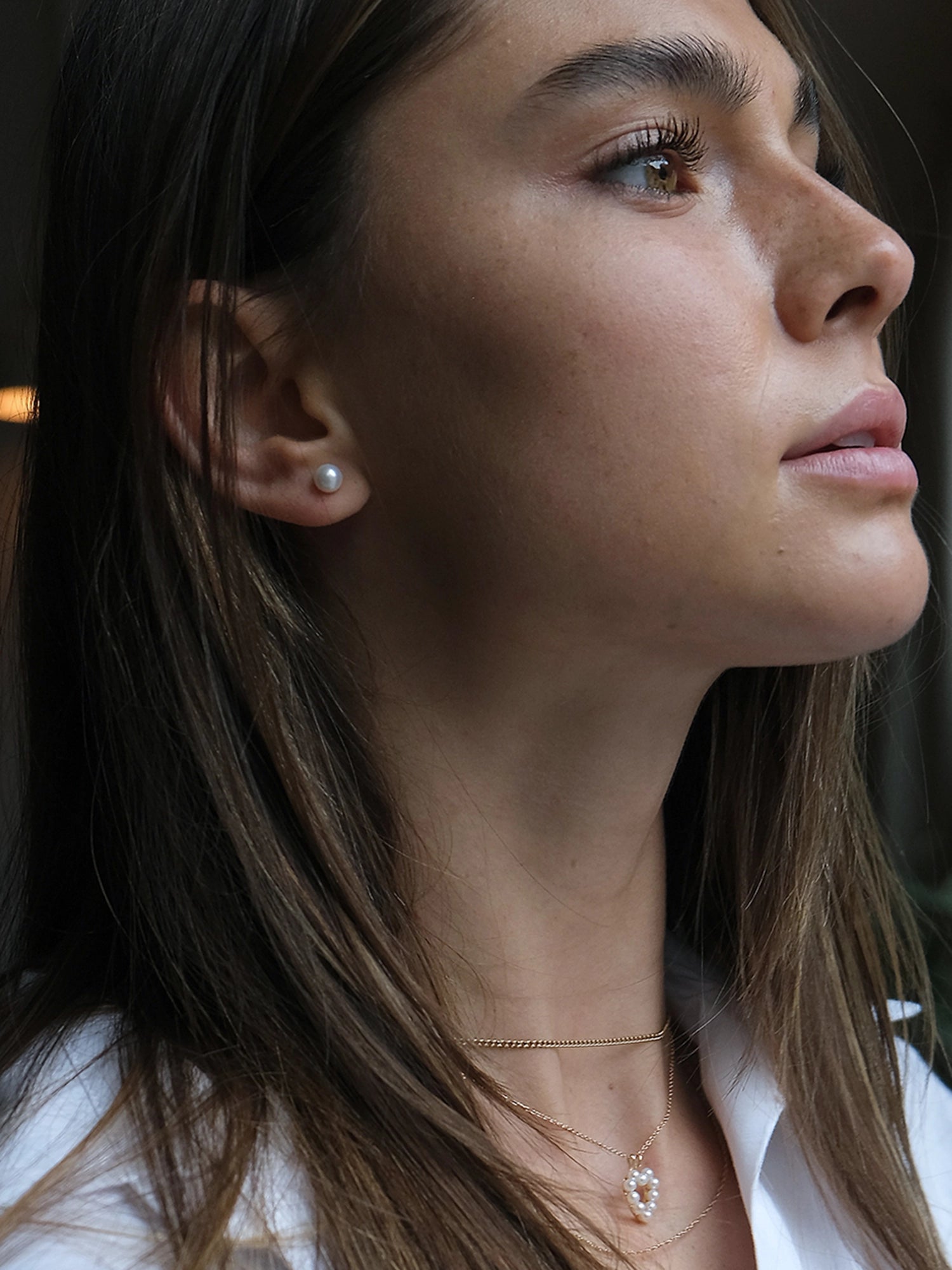 14kt Gold Mini Studs - 6-7mm white round freshwater pearl earrings in 14kt yellow gold by Nishi Pearls, worn on a model