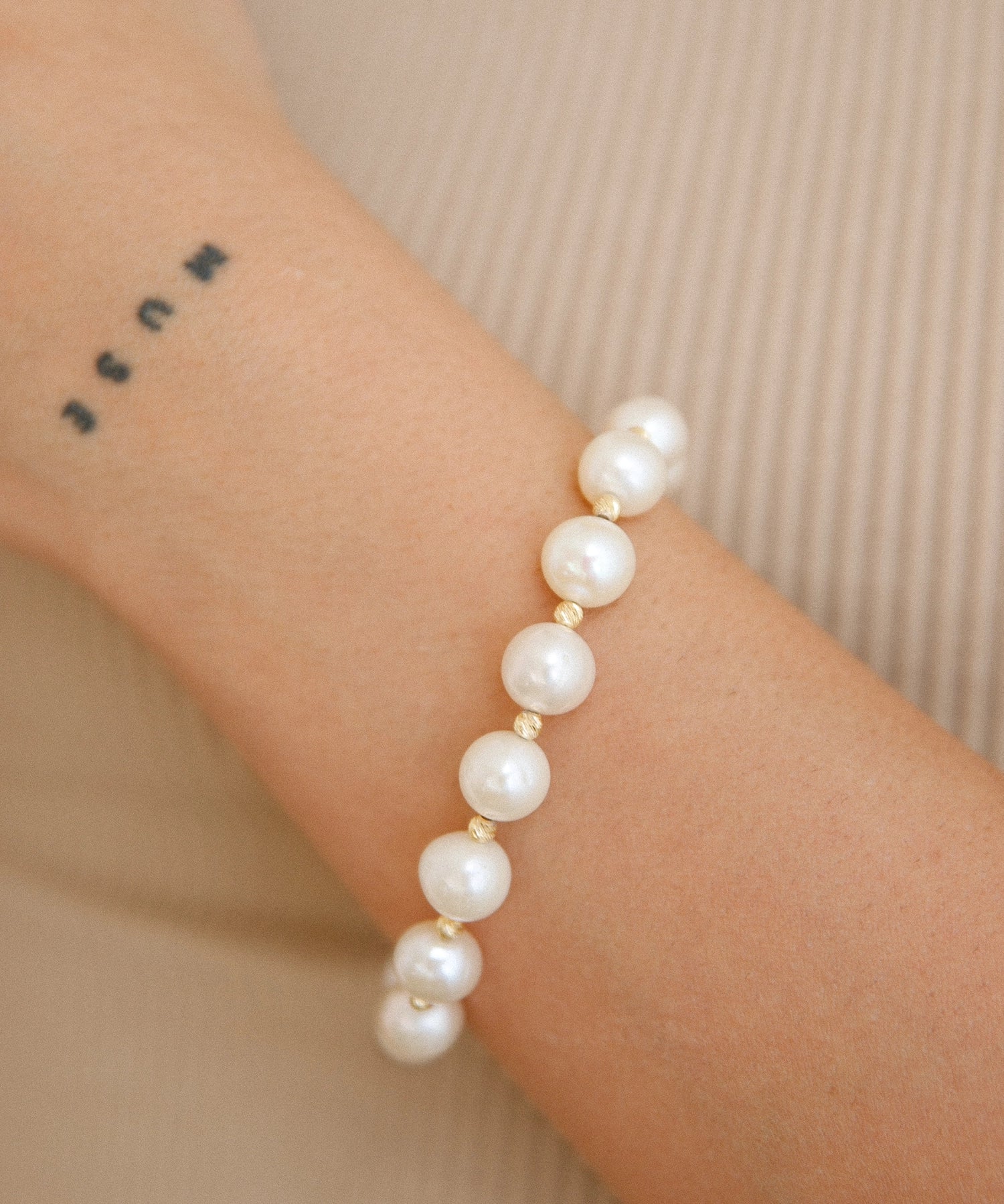 Gold Bead Bracelet - 9-10mm white freshwater pearl bracelet in yellow gold plated silver by Nishi Pearls, worn on a model