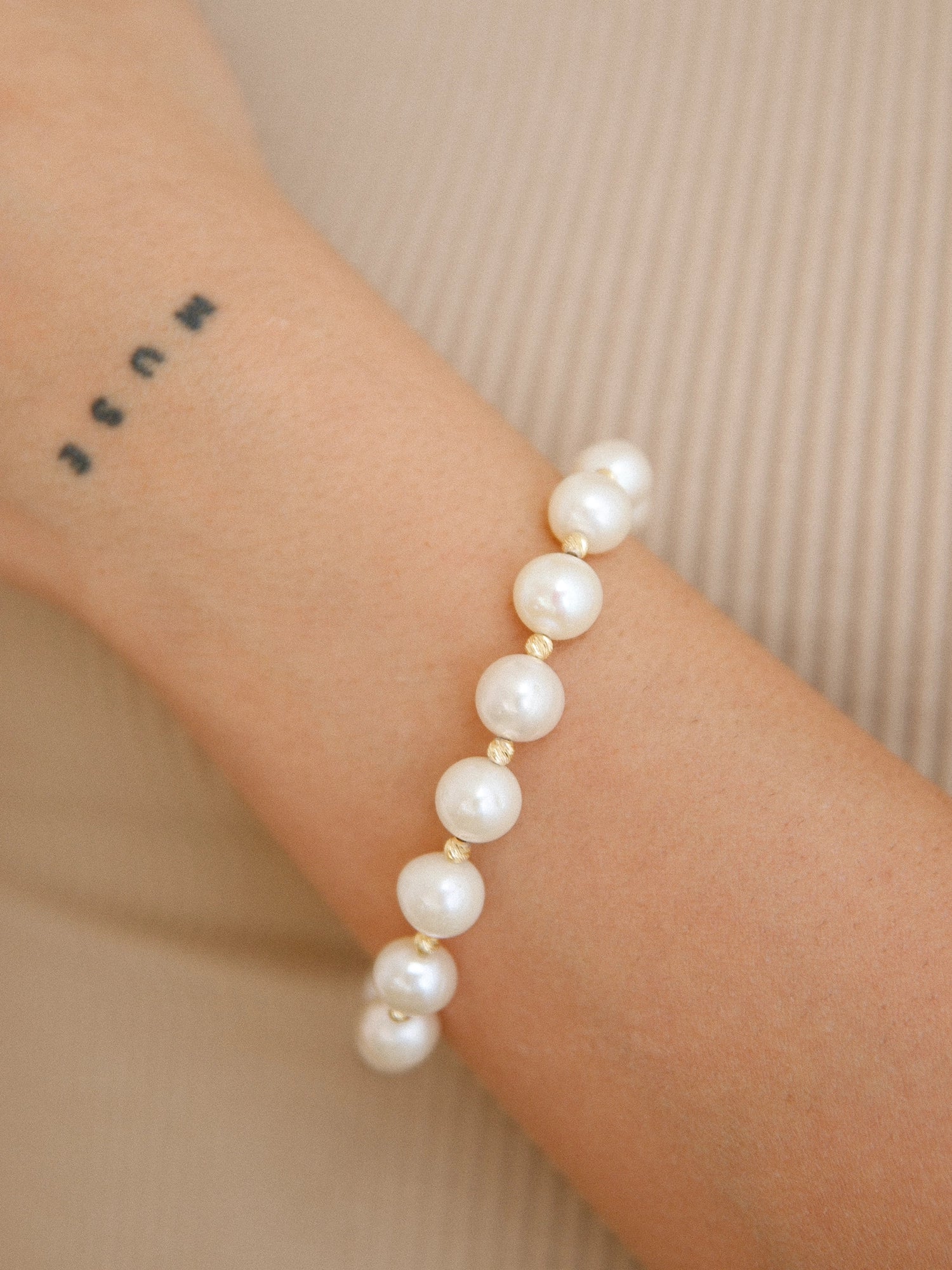 Gold Bead Bracelet - 9-10mm white freshwater pearl bracelet in yellow gold plated silver by Nishi Pearls, worn on a model