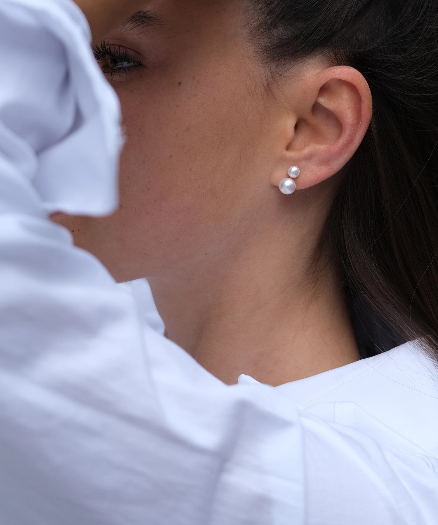 Multi Pearl Studs - mixed-size white button freshwater pearl earrings in 14kt yellow gold by Nishi Pearls, worn on a model